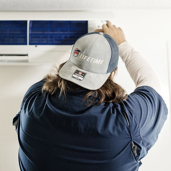 Lifetime Heating, Cooling, Plumbing & Electric working on indoor wall-mounted unit.