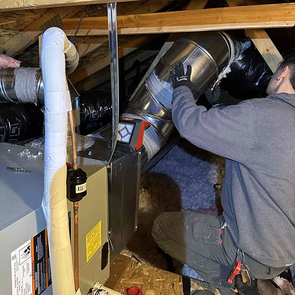 Lifetime Heating, Cooling, Plumbing & Electric technician working on air ducts.