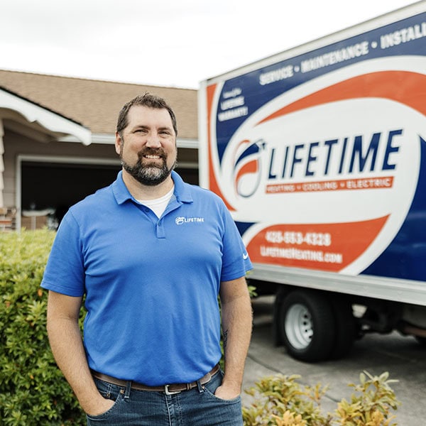Lifetime Heating, Cooling, Plumbing & Electric employee in front of company box truck.