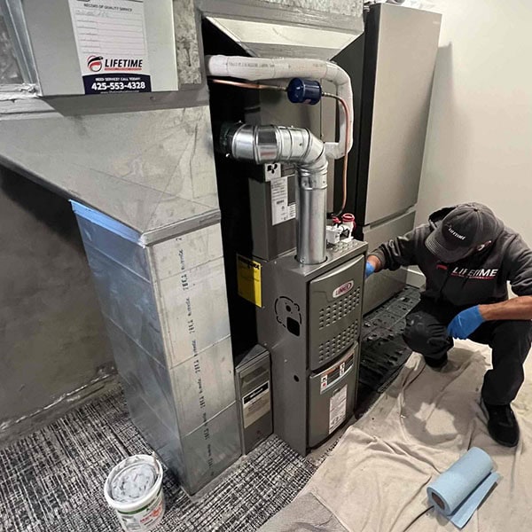 Lifetime Heating, Cooling, Plumbing & Electric technician working on residential furnace.