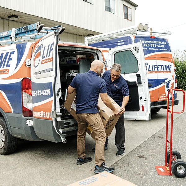 Lifetime Heating, Cooling, Plumbing & Electric technicians unloading box from van.