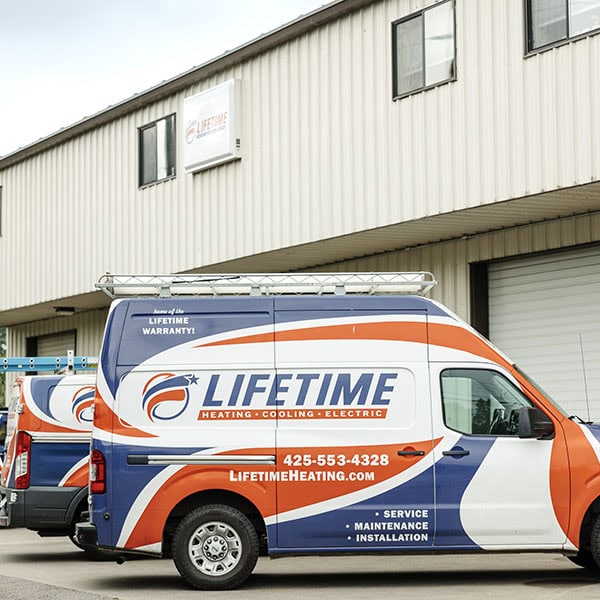 Lifetime Heating, Cooling, Plumbing & Electric vehicles outside of warehouse.
