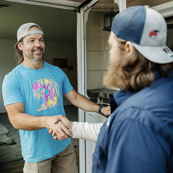 Lifetime Heating, Cooling, Plumbing & Electric technician shaking residential customers hand.