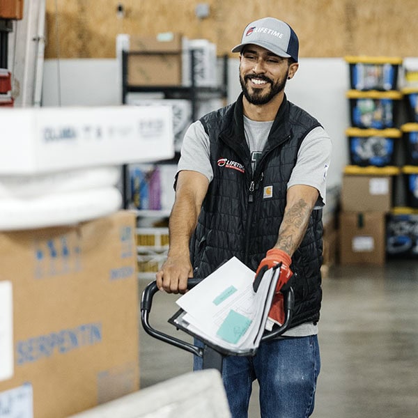 Lifetime Heating, Cooling, Plumbing & Electric employee pushing pallet in warehouse.