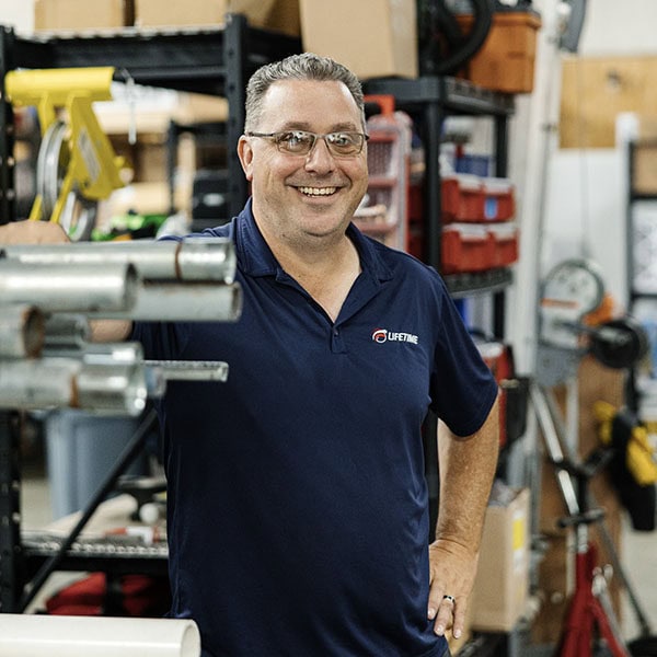 Lifetime Heating, Cooling, Plumbing & Electric employee in warehouse smiling at camera.