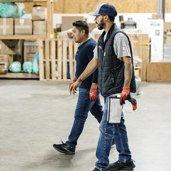 Lifetime Heating, Cooling, Plumbing & Electric employees walking in warehouse.